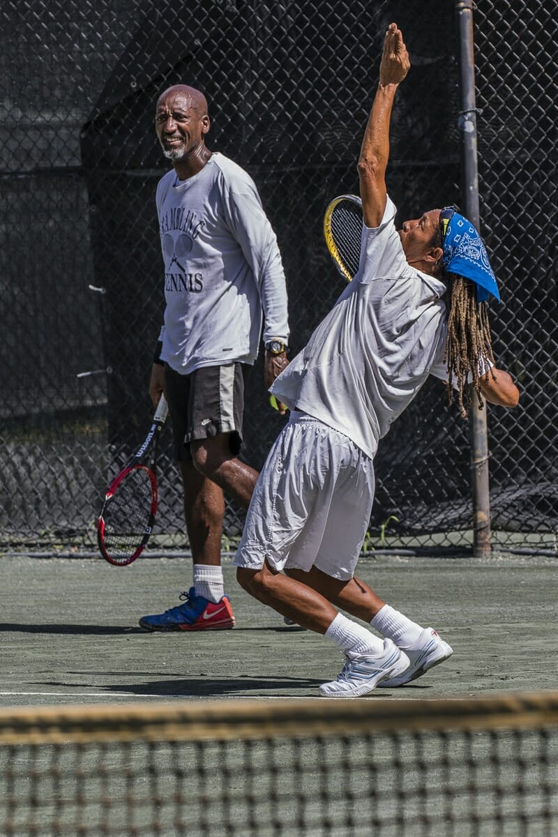 Larry Scheper serves while partner Kenny Meyers looks on.