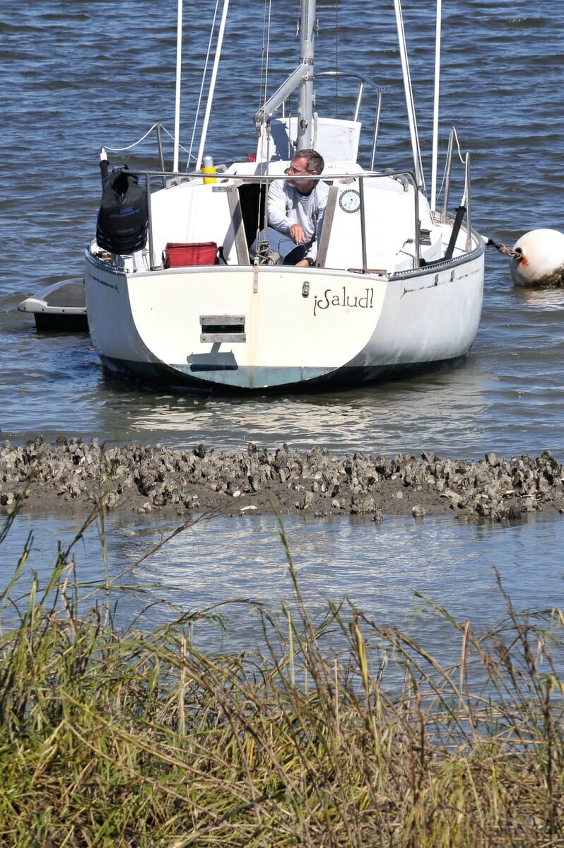 An unidentified man bails water from his sailboat that nearly ran aground in Factory Creek. Photo by Bob Sofaly.