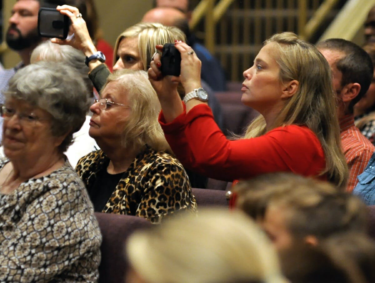 Friends and family take photos of their students on stage.