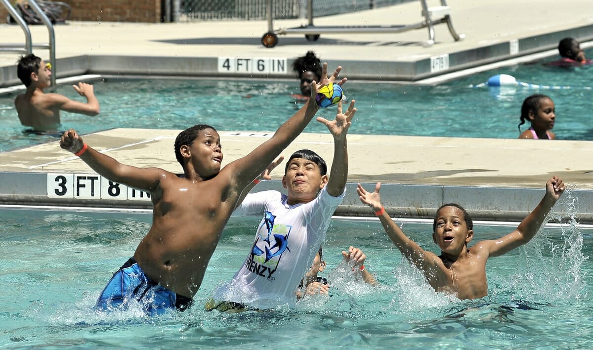 Three boys have some fun with a ball during the summer in the pool of Charles “Lynd” Brown Community Activity Center.