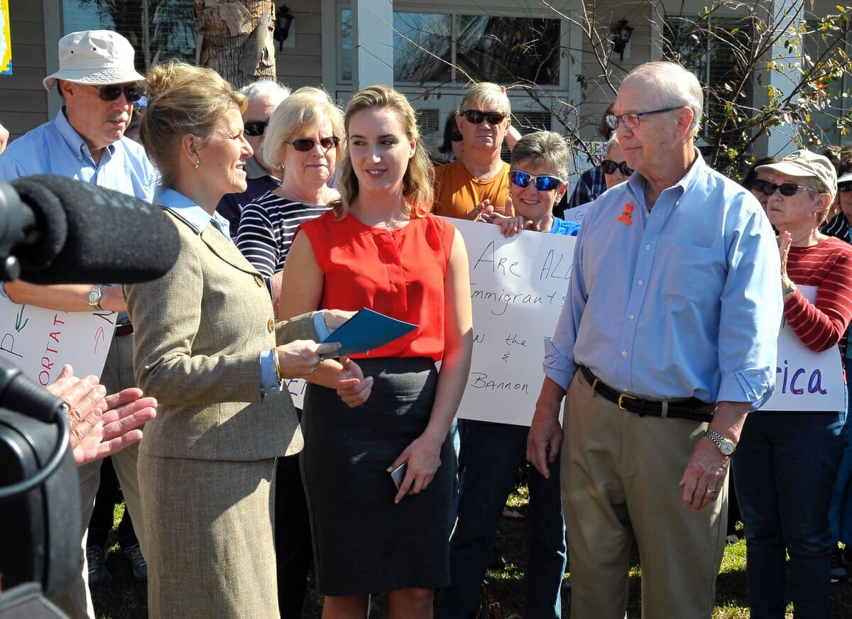 Special Representative Cris Steele, left, and Field Representative Sarah Kimball, center, of Rep. Mark Sanford’s office, accept a letter from George Kanuck during a rally regarding immigration.