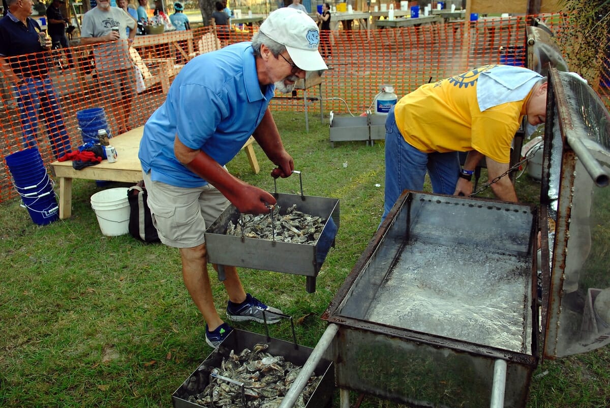 Kerry Bunton, left, of the Rotary Club of the Lowcountry, loads some of the 75 bushels of fresh oysters into a steamer to kick off the 21st annual Family Oyster Roast in Port Royal. At right, fellow Rotarian Andy Thacker adjusts the heat. 