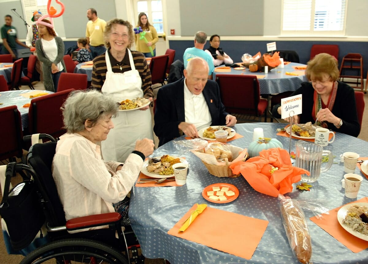 Patrons are seated at tables after which volunteers come and take their “order” and deliver Thanksgiving meals at St. Helena Episcopal Church.